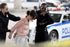 Woman in handcuffs being led away by police, symbolizing the need for a dedicated South Jersey criminal defense lawyer.