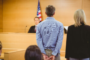 Man in handcuffs standing in court, highlighting the importance of experienced criminal defense representation in New Jersey.